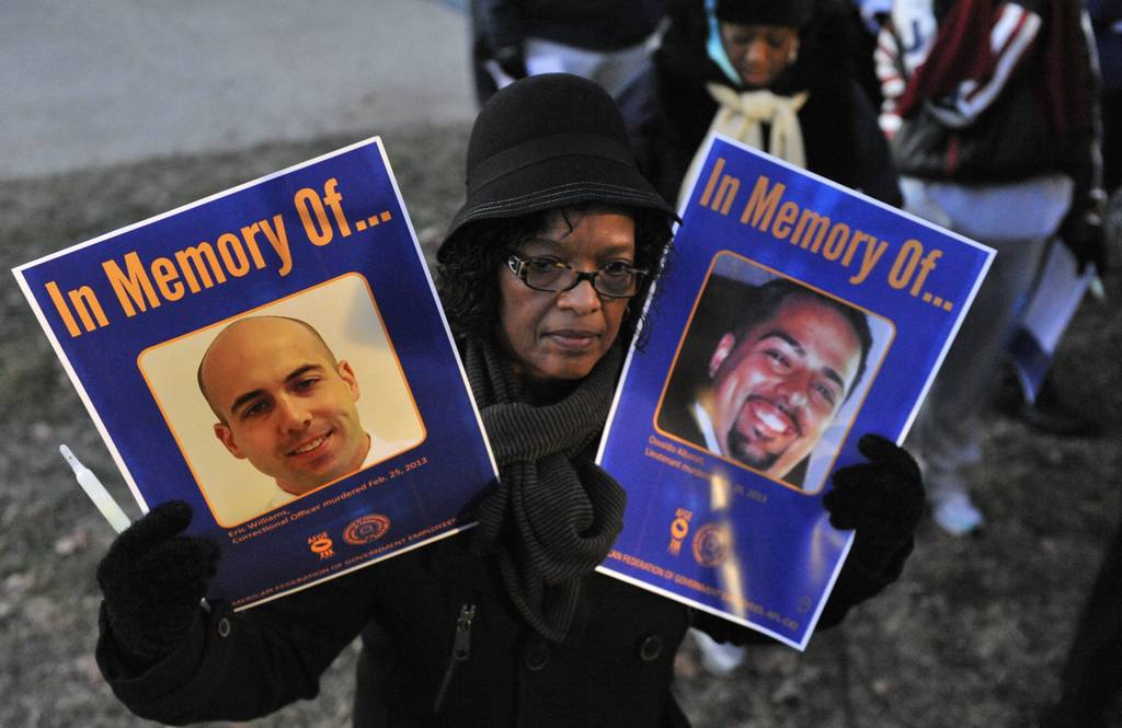 An AFGE member holds up a sign with the images of Eric Williams and Osvaldo Albarati - two Bureau of Prison employees who were murdered on the job. 