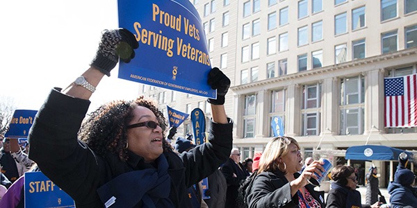 Black woman holding rally sign out side of VA headquarters that reads Proud Vets Serving Veterans