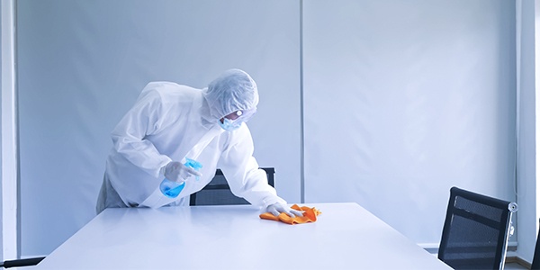 Person wearing PPE cleaning a conference room