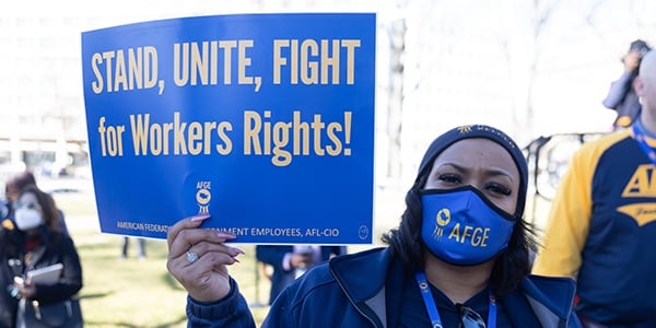 AFGE activist holding sign that says Stand, Unite, Fight for Workers Rights