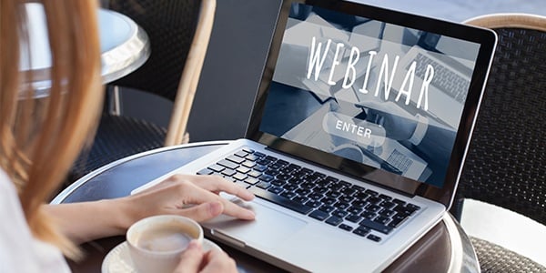 Person sitting in front of a laptop that says webinar
