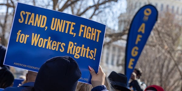 Activist holds sign that reads Stand, Unite, Fight for Workers' Rights